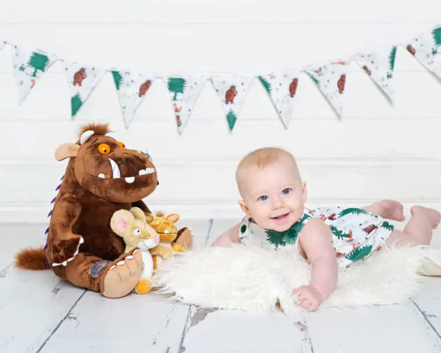 a little boy with a gruffalo toy in a gruffalo themed romper