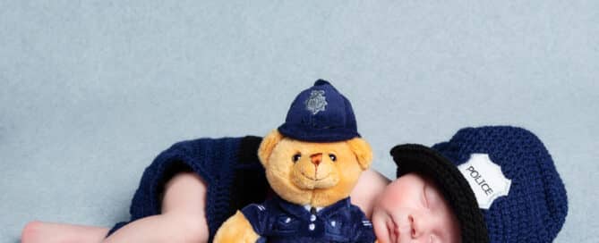 a sleeping newborn in a crocheted police outfit