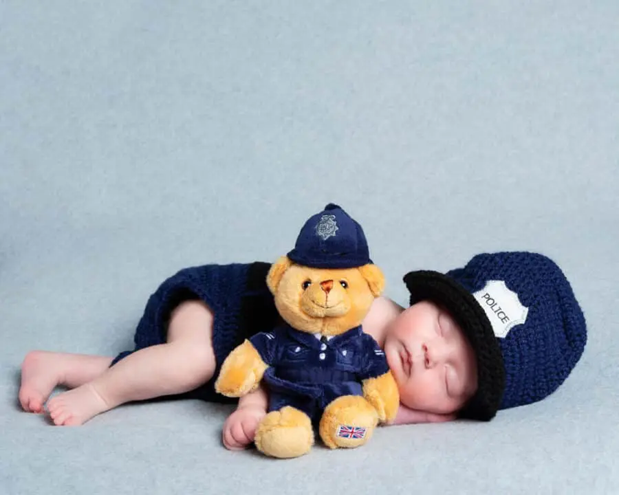 a sleeping newborn in a crocheted police outfit