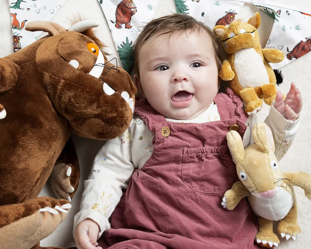 a little girl laying down with some Gruffalo Toys
