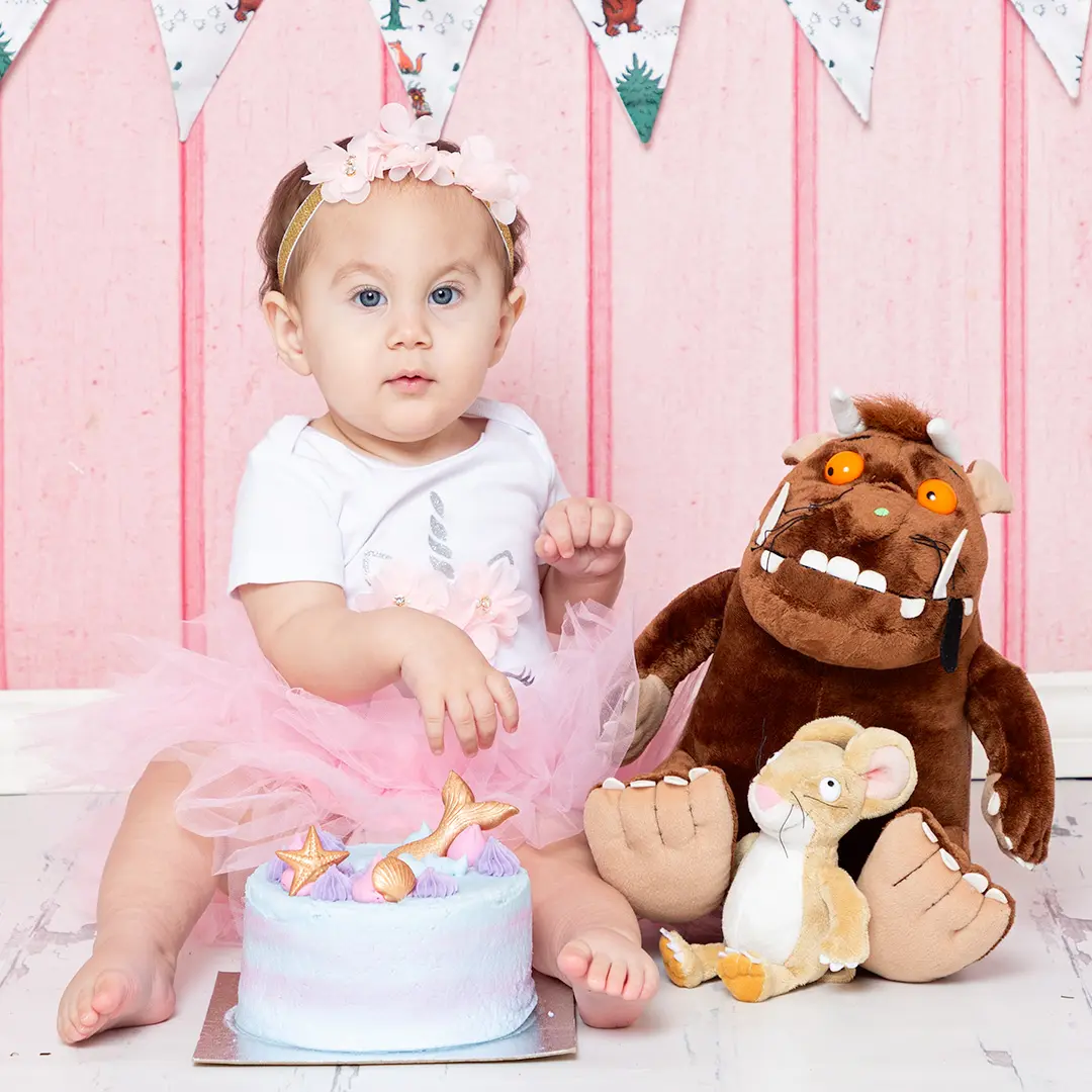 a little girl with a cake and some Gruffalo toys