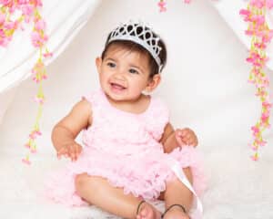 a little girl in a pink dress wears a silver tiara