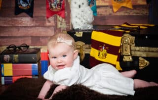 a little girl in a white dress amongst Harry Potter props
