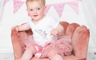 a little girl plays on a pink chair a photo shoot