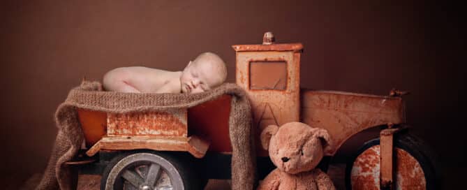 a digitally composited image of a newborn in a metal truck