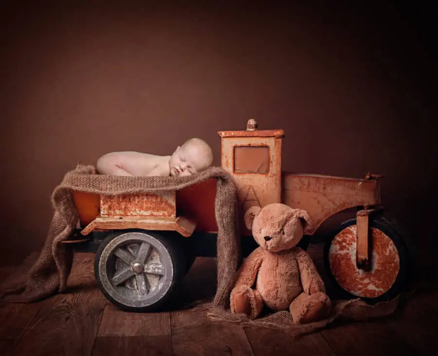 a digitally composited image of a newborn in a metal truck