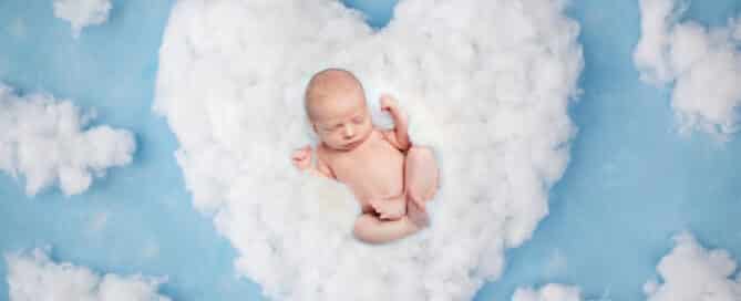 A digital image of a newborn sleeping in a heart shaped cloud