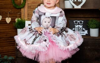 a little girl in a dress iwth photos printed on it at my father's day photo shoot in 2022