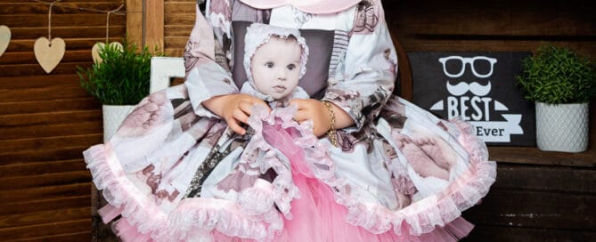 a little girl in a dress iwth photos printed on it at my father's day photo shoot in 2022