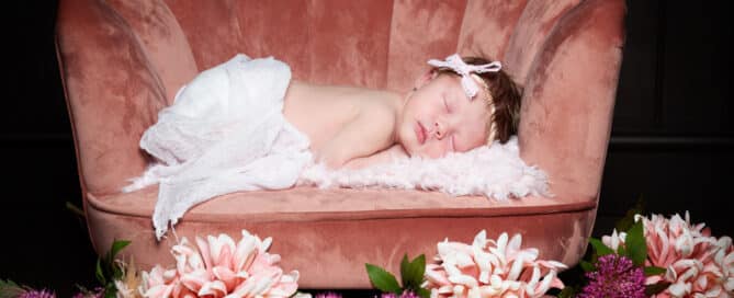 a baby sleeps on a pink chair with matching flowers