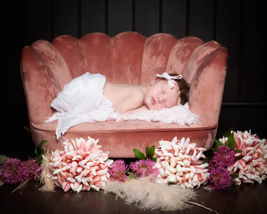 a baby sleeps on a pink chair with matching flowers