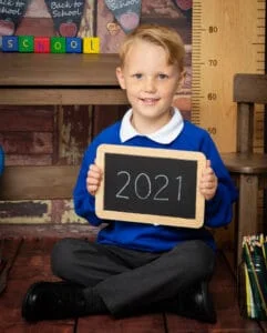 a little boy poses in his school uniform at a school themed photo shoot in 2021