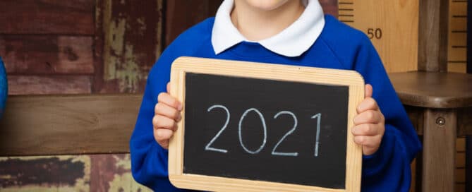 a little boy poses in his school uniform at a school themed photo shoot in 2021