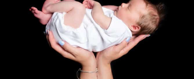 a sleeping newborn cradled in their mums hands