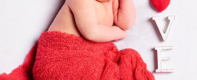 a newborn sleeps next to letters spelling love