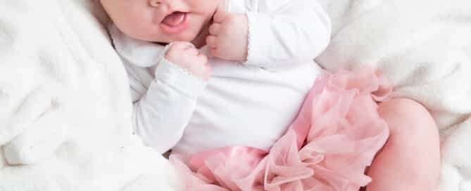 an older newborn baby at a professional photo shoot in a pink tutu
