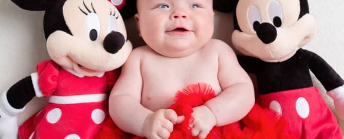 a little baby with a mickey and minnie stuffed toy