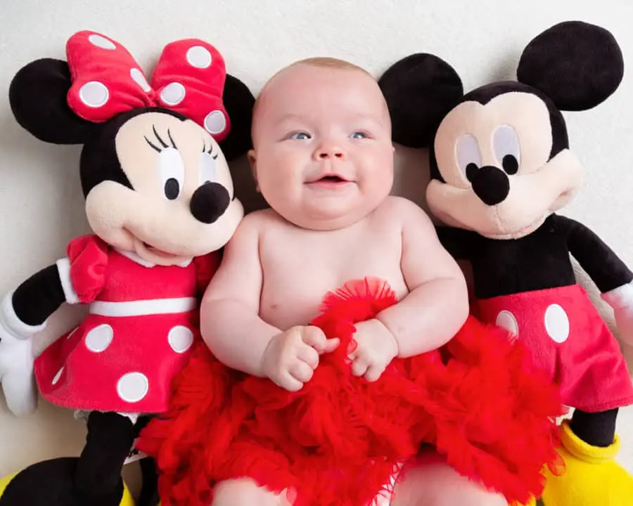 a little baby with a mickey and minnie stuffed toy