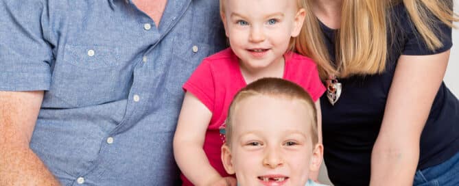 a mum and dad pose with their son and daughter sitting on the floor