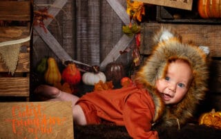 a little boy dressed as a fox in a pumpkin themed phot o shoot set