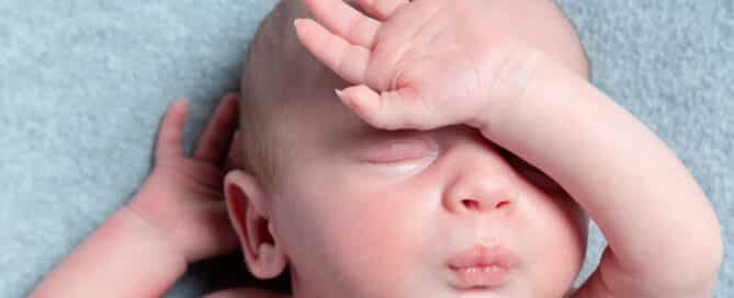 a newborn pouting with their hand over their face like they've had enough of the day