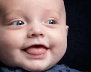 a close up of a smiling baby against a dark background in my studio