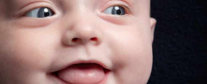 a close up of a smiling baby against a dark background in my studio