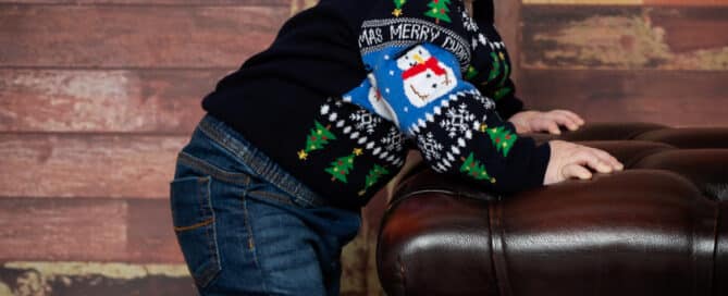 a little boy in a christmas jumper against a dark wood background