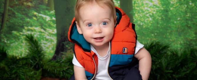 a little boy in an anorak against a woodland backdrop