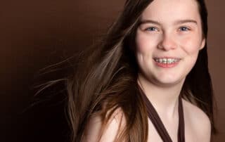 a young lady poses in a brown dress for a professional photo