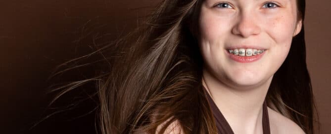 a young lady poses in a brown dress for a professional photo