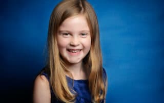 A young lady poses in a blue dress for a professional photo shoot