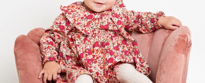 a little girl in a flowery dress on a pink chair at my studio