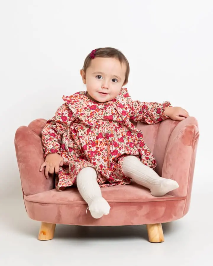 a little girl in a flowery dress on a pink chair at my studio