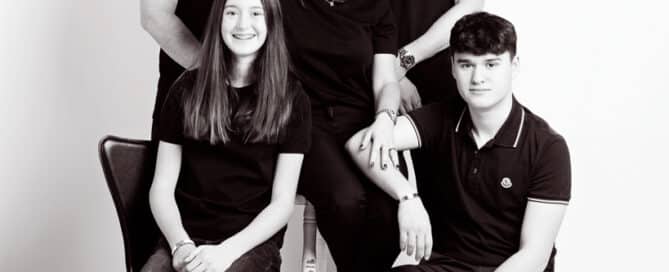 a black and white image of a family posing all dressed in black