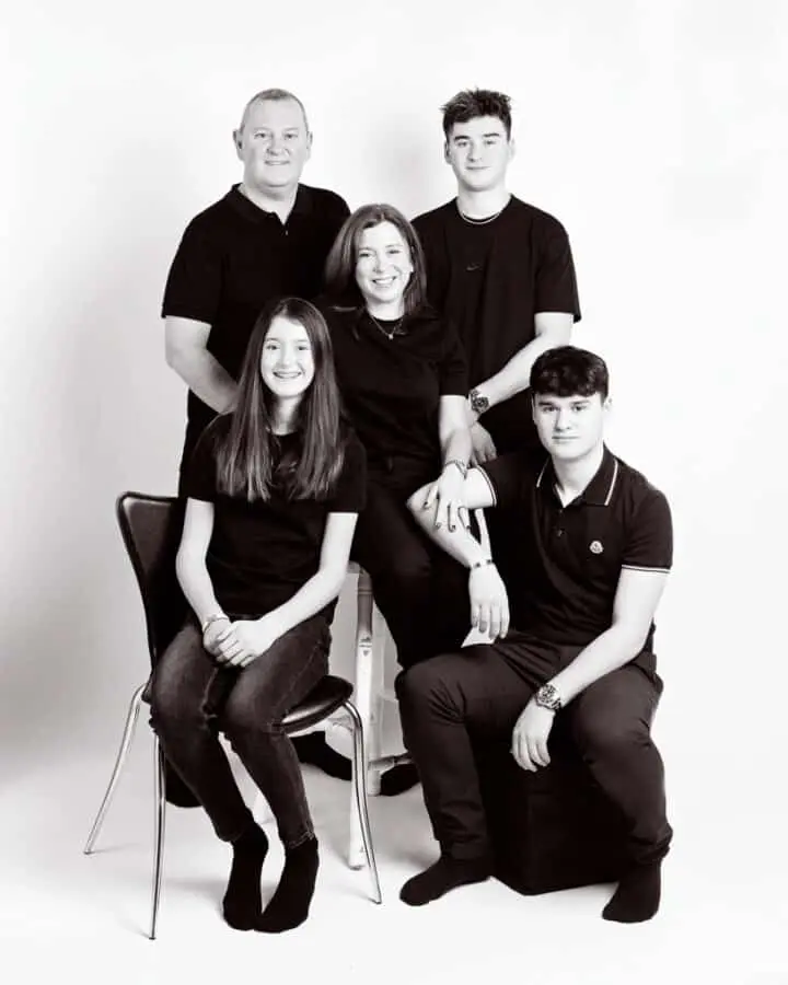 a black and white image of a family posing all dressed in black