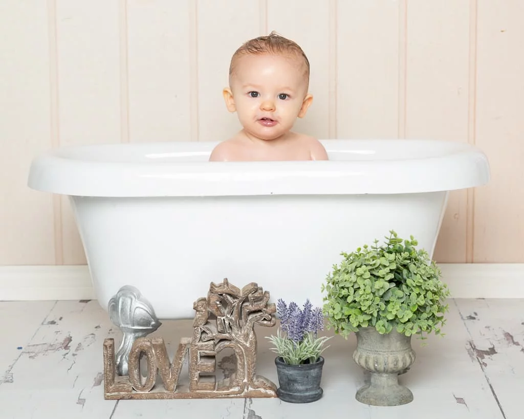 a little girl in a white bathtub with the love and lavender accessories