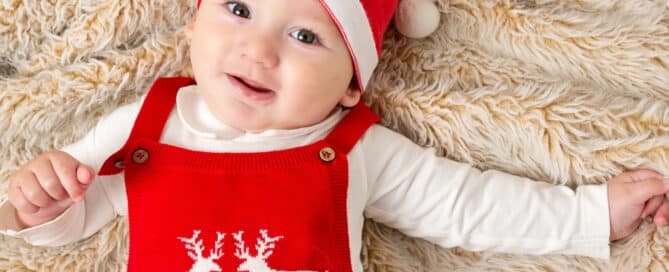 a baby on a fluffy blanket wearing a festive outfit and santa hat
