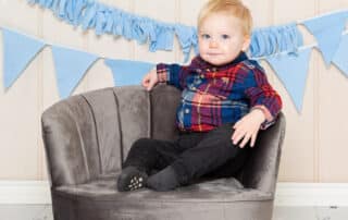 a little boy strikes a pose on a grey armchair