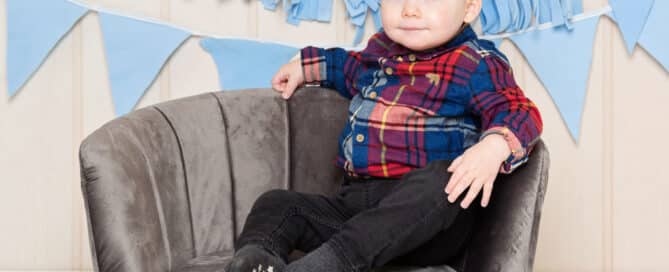 a little boy strikes a pose on a grey armchair