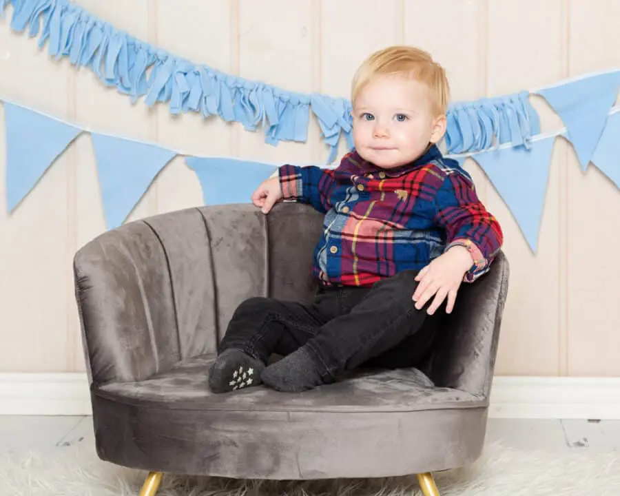a little boy strikes a pose on a grey armchair
