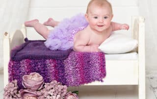a baby on my mini white bed with purple accessories