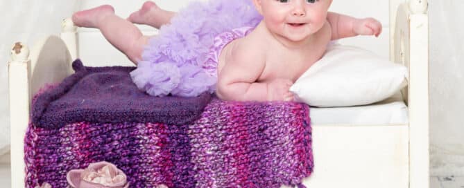 a baby on my mini white bed with purple accessories