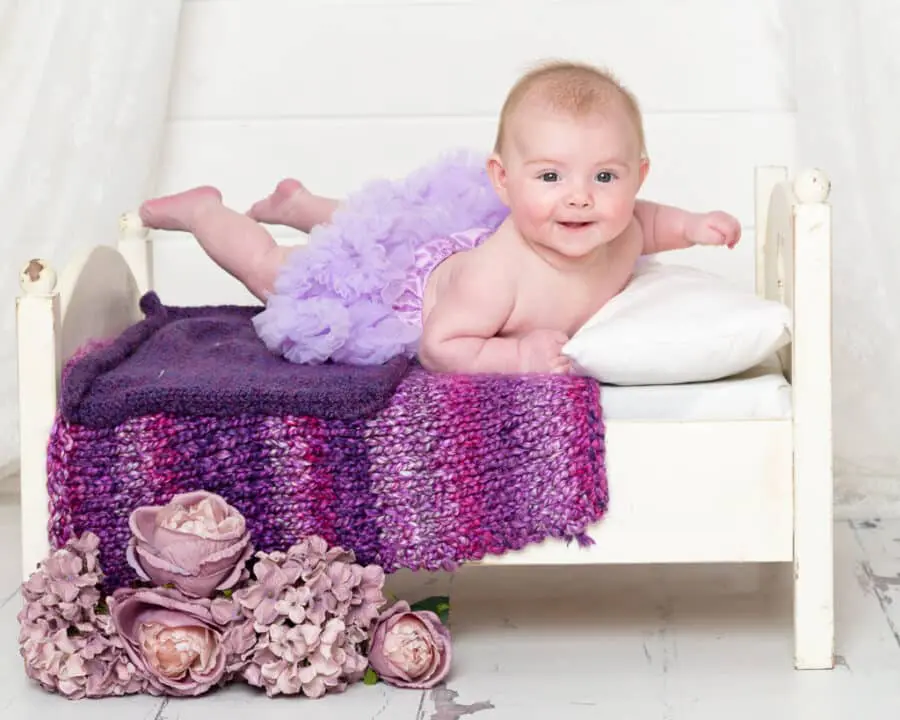 a baby on my mini white bed with purple accessories