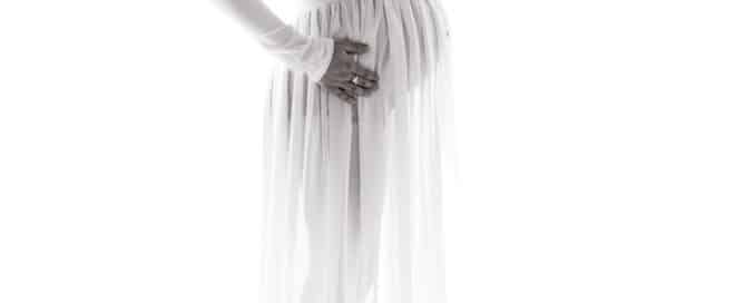 a pregnant lady in a sheer white maternity gown