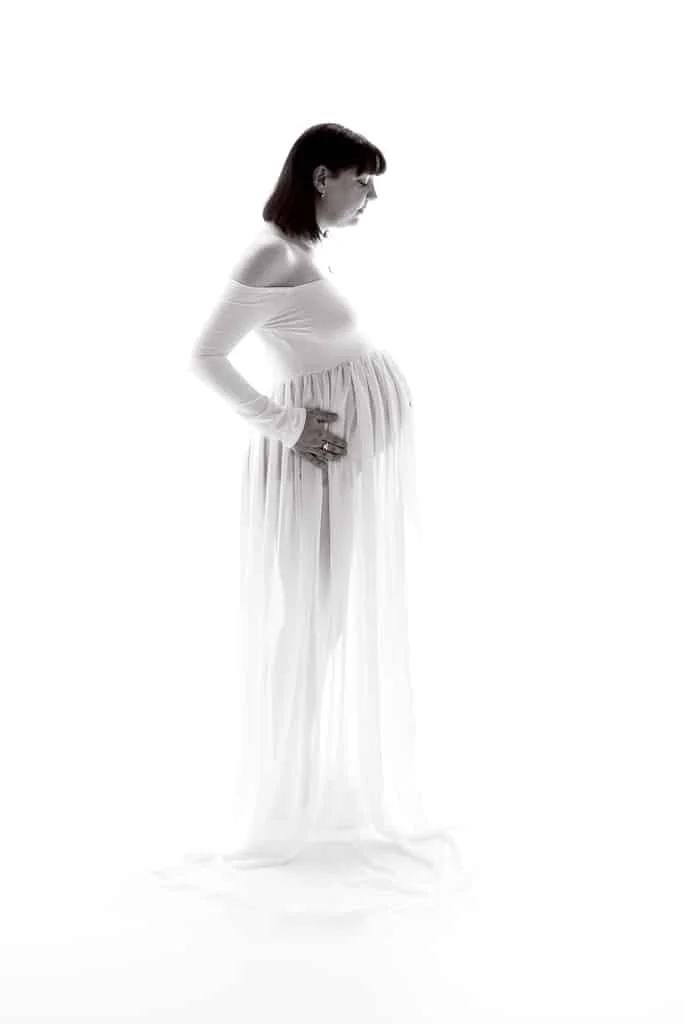 a pregnant lady in a sheer white maternity gown