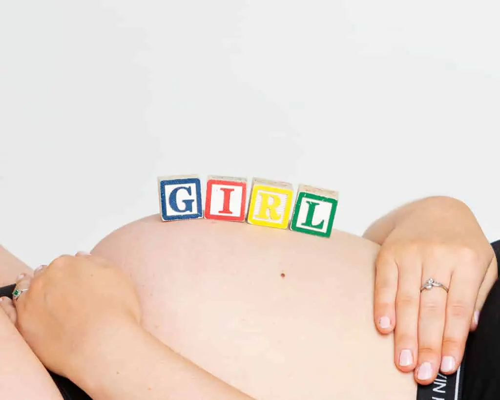 a pregnant belly with letter blocks spelling girl on it