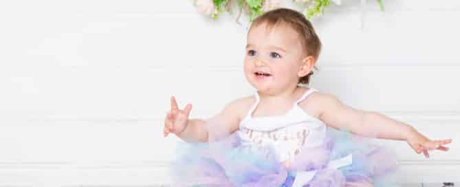 A little girl in a pastel tutu is enjoying herself as she gets into her cake smash photo shoot