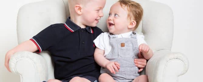 two male slbings pose for photos but looking into each others eyes and smiling