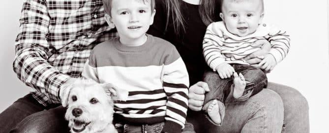 a black and white image of a family posing with their dog